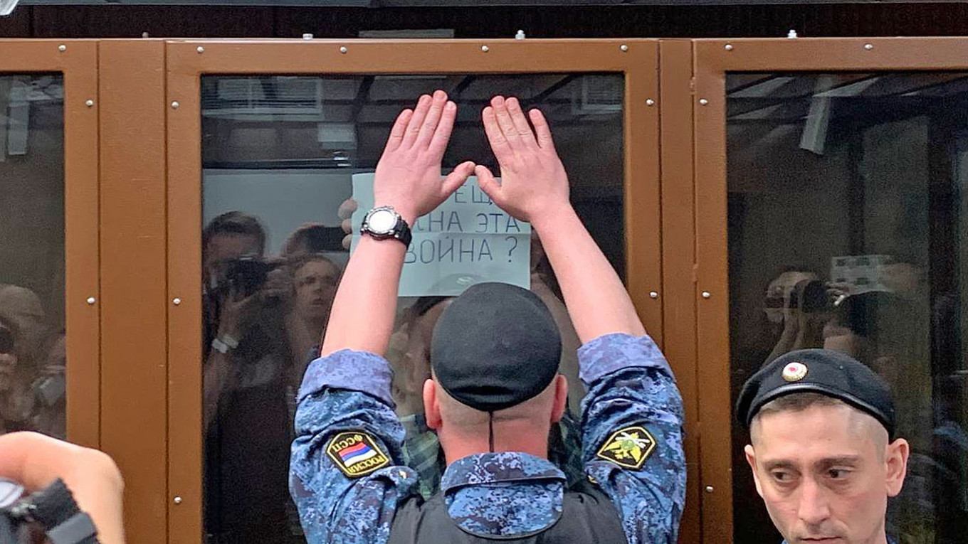 Пристав пытается закрыть плакат «Вам еще нужна эта война?», который показывает Горинов. Фото: RTVi