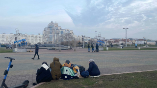 Группа женщин-мигрантов сидит на площади в центре Минска.