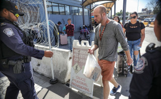  Сотрудник Погранично-таможенной службы США проверяет документы пешеходов на переходе Сан-Исидро между Тихуаной, Мексика, и Сан-Диего, Калифорния