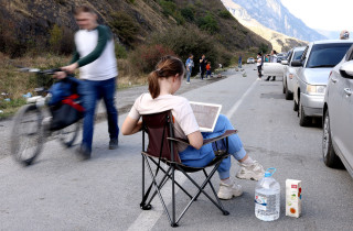 Женщина с ноутбуком у колонны автомобилей на российско-грузинской границе, сентябрь 2022 г. 