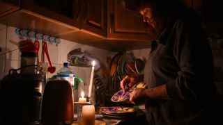 Ирен Роздобудько, 60-летний писатель и преподаватель университета, моет посуду при свечах в своем доме на севере Киева