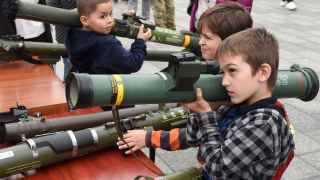 Дети держат тубусы от Javelin, NLAW, Stinger и другого оружия, используемого украинскими военными, на выставке под открытым небом во Львове.