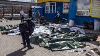 Украинский полицейский у тел, накрытых брезентом, после ракетного обстрела на вокзале Краматорска. Жертвами удара стали 57 человек.