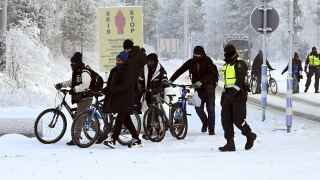 Финский пограничник и мигранты с велосипедами на международном пограничном переходе в Салле