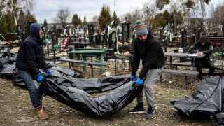 Рабочие складывают тела для опознания на кладбище в Буче.