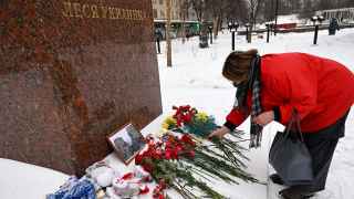Женщина возлагает цветы к подножию памятника Лесе Украинке в Москве в память о погибших в Днепре