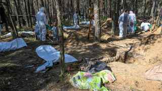 Судебно-медицинские эксперты на месте массового захоронения в лесу на окраине Изюма