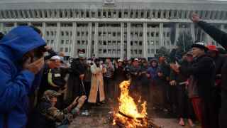 В ночь на 6 октября протестующие в Бишкеке собираются у костра перед захваченным главным правительственным зданием, известным как Белый дом.
