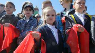 Дети держат в руках ярко-красный шейный платок — символ пионеров.

