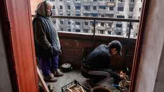 Жители Мариуполя разводят костер на балконе в жилом доме, чтобы приготовить поесть.