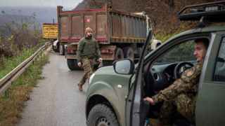 Латвийские солдаты, входящие в состав миротворческой миссии НАТО в Косово, возле тяжеловозов, которыми сербы заблокировали дорогу возле деревни Угларе на севере Косова