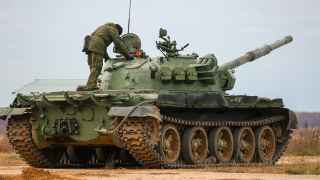 Мобилизованный военный поднимается на танк Т-62 в рамках боевой подготовки на военном полигоне